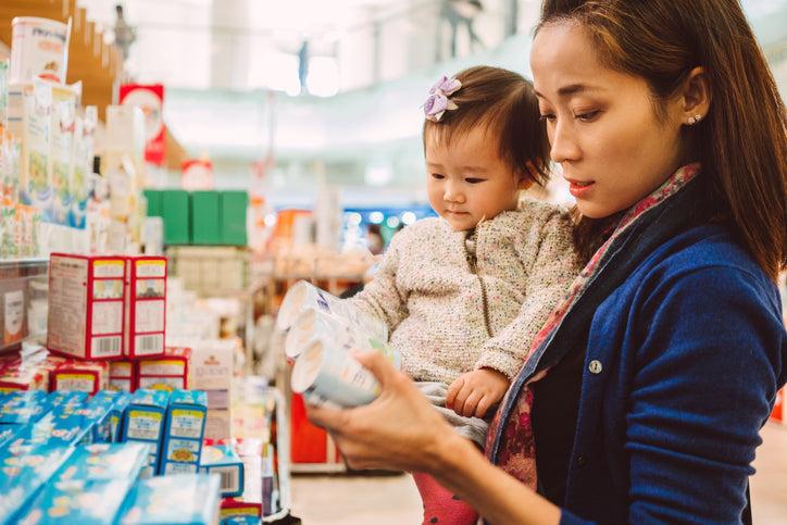 Hình ảnh phụ huynh kiểm tra thông tin thành phần và dinh dưỡng trên bao bì sản phẩm trước khi lựa chọn đồ ăn nhẹ cho trẻ.